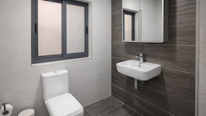 A modern bathroom with a toilet, sink, and window. - Cozy Double Room in Pembroke (Pembroke)