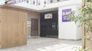 A building entrance with a gated driveway, a signboard, and a balcony with plants. - BLOOM STAY  (Amritsar)