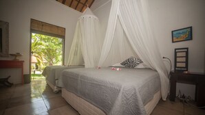 Une chambre à coucher avec un lit placé sous un baldaquin blanc, une table de chevet, une chaise et une vue sur l’extérieur.