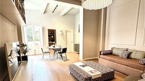 Ein modernes Wohnzimmer mit Sofa, Hocker und Essbereich.