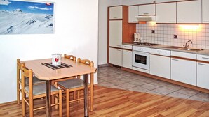 A compact kitchen with white cabinets, a wooden dining table, and a coffee maker. - Kristall by Interhome (Prutz/Kaunertal)