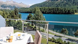 Uma mesa com itens de café da manhã e vista para um lago e montanhas.