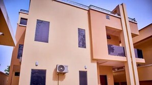Un immeuble à plusieurs étages doté d’une façade plane, de plusieurs fenêtres et d’un appareil de climatisation fixé sur le mur extérieur.