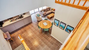 Une cuisine moderne avec un coin repas, un canapé et un escalier.