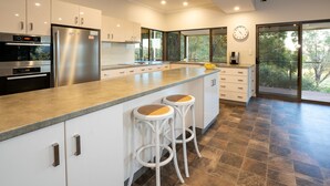 A modern kitchen with a large island, stainless steel appliances, and a view of the outdoors. - Valley View – Ferguson Valley (Ferguson)