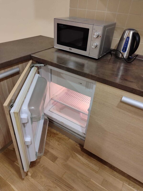Una cocina compacta con microondas integrado y un refrigerador pequeño.