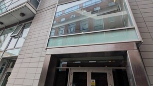 Un edificio moderno con fachada de vidrio, un juego de puertas dobles y una escalera visible que conduce a un nivel superior.