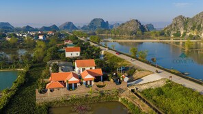 A residential area with houses, a road, and a body of water. - Cometa Villas Ninh Bình (Gia Vien)