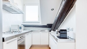 Una cocina moderna con armarios blancos, horno empotrado, microondas y cafetera.
