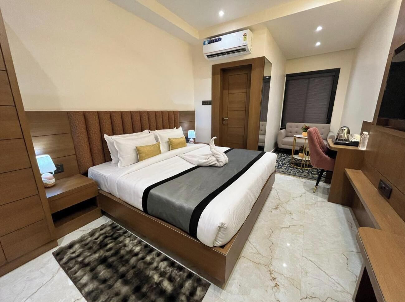Una moderna camera d'albergo con un grande letto, una scrivania, una sedia e un condizionatore.