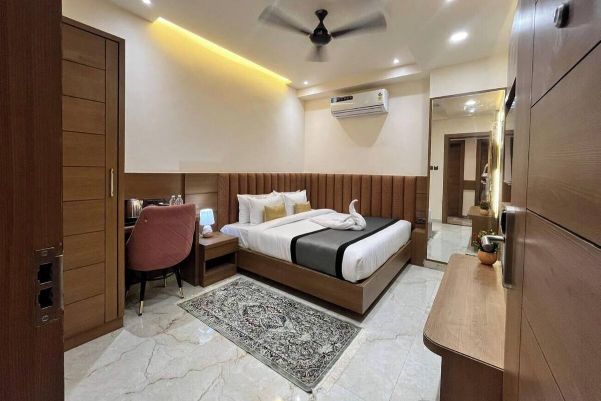 A modern hotel room with a bed, bedside table, chair, and a small desk area.