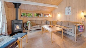 Tunnelmallinen mökin sisustus, jossa on sohva, pöytä ja puuhella.