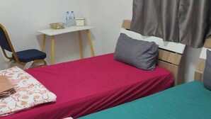 A small, simple room with two beds, a chair, a small table, and a window with curtains. - Natcha Place Klongluang 35 (Khlong Luang)
