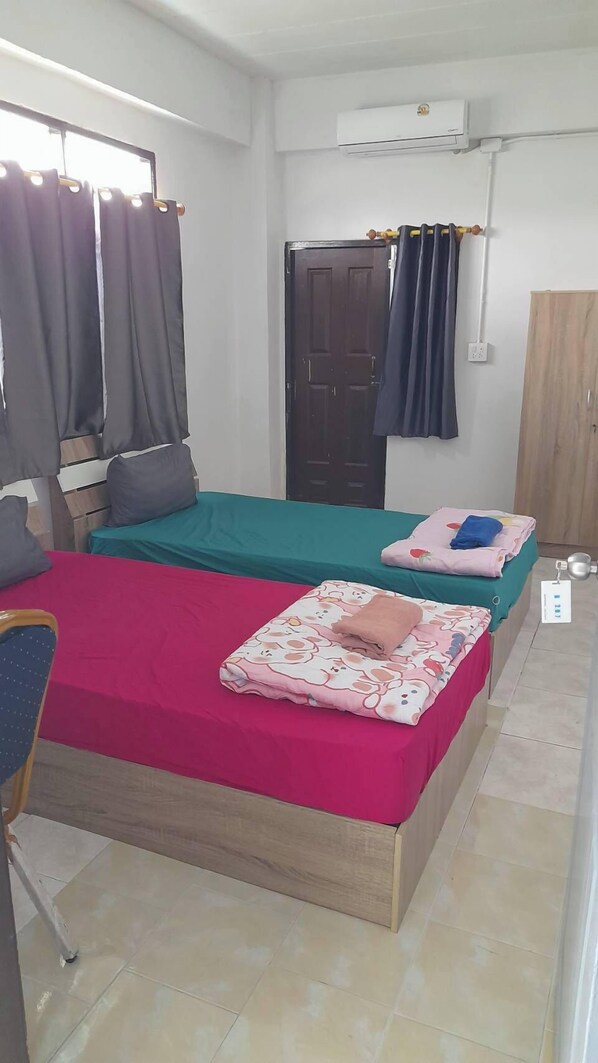 A room with two beds, a desk, an air conditioner, and a wardrobe.