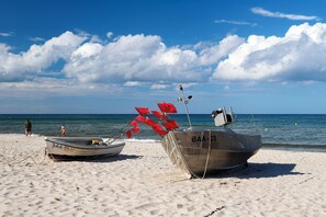Två båtar på en sandstrand med en klar himmel och havet i bakgrunden.