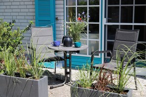 En liten sittplats utomhus med ett bord, stolar och krukväxter.