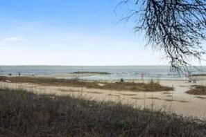 A beach with a clear sky, sandy shore, and sparse vegetation. - Beach Bliss Villa with Scenic Ocean Views (Hilton Head Island)