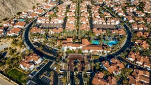 An aerial view of a residential area with a central circular plaza, a swimming pool, and a stop sign.