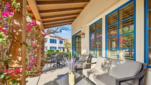 Eine Terrasse im Freien mit einer Holz-Pergola, einer Couch und einem Blumenstrauß.