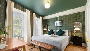 Une chambre avec un grand lit, des lampes de chevet, un banc et une vue sur l’extérieur.