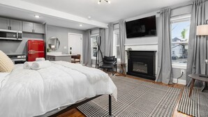 Une chambre d’hôtel moderne dotée d’un grand lit, d’une télévision à écran plat, d’une cheminée et d’un coin cuisine.