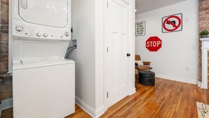 A laundry room with a washer and dryer, a white door, a stop sign, and a no right turn sign on the wall.