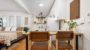 A compact living space with a bed, a dining table with two chairs, a kitchen area, and a small seating area with a sofa. - Modern Loft In the Heart of OSU Campus (Columbus)