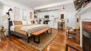A modern bedroom with a large bed, a bench, and a fireplace. - Modern Loft In the Heart of OSU Campus (Columbus)
