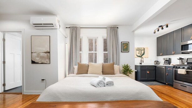 Une chambre d’hôtel moderne dotée d’un grand lit, d’une table en bois, d’une kitchenette et offrant une vue sur la ville.
