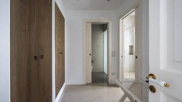 A hallway with wooden doors, a white door leading to a bathroom, and a white door with a brass handle.