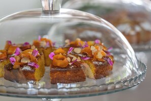 A glass-covered dessert display with slices topped with nuts and flowers.