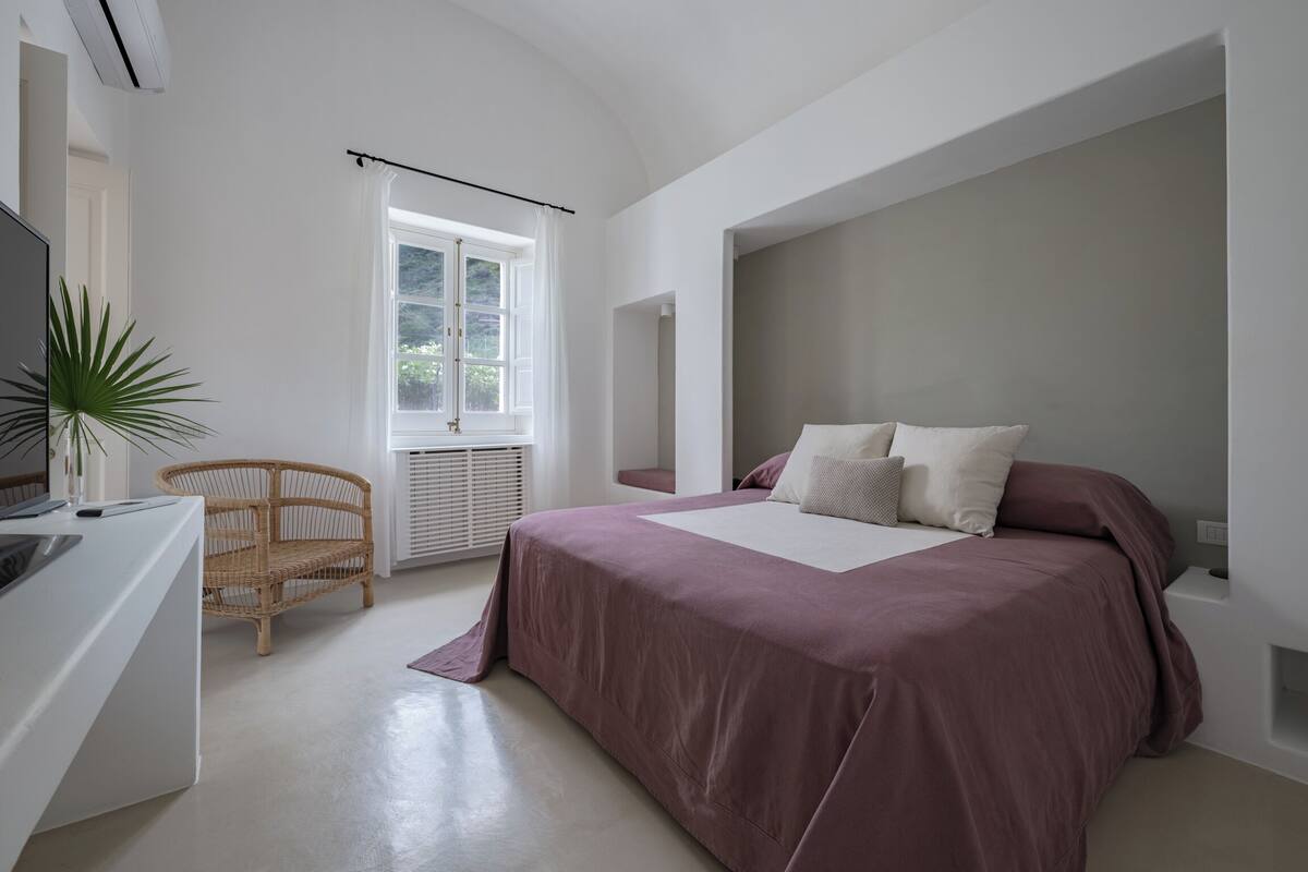 Ein Schlafzimmer mit einem großen Bett, einem Schreibtisch, einem Stuhl und einem Fenster.