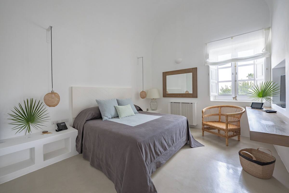 Ein modernes Schlafzimmer mit Bett, Nachttisch, Lampe, Stuhl und Schreibtisch mit Laptop.