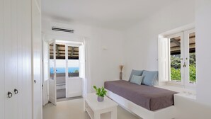 Une chambre à coucher moderne avec un lit, une petite table blanche et une plante en pot.