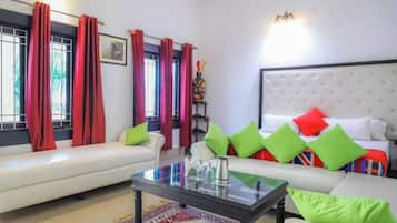 A modern living room with a sofa, a coffee table, and a bed with colorful pillows.