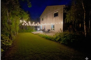 Una casa con patio, jardín y luces colgantes.