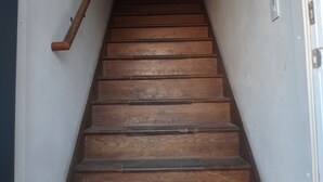 Un escalier en bois, doté d’une rampe, mène à une porte fermée située en haut.