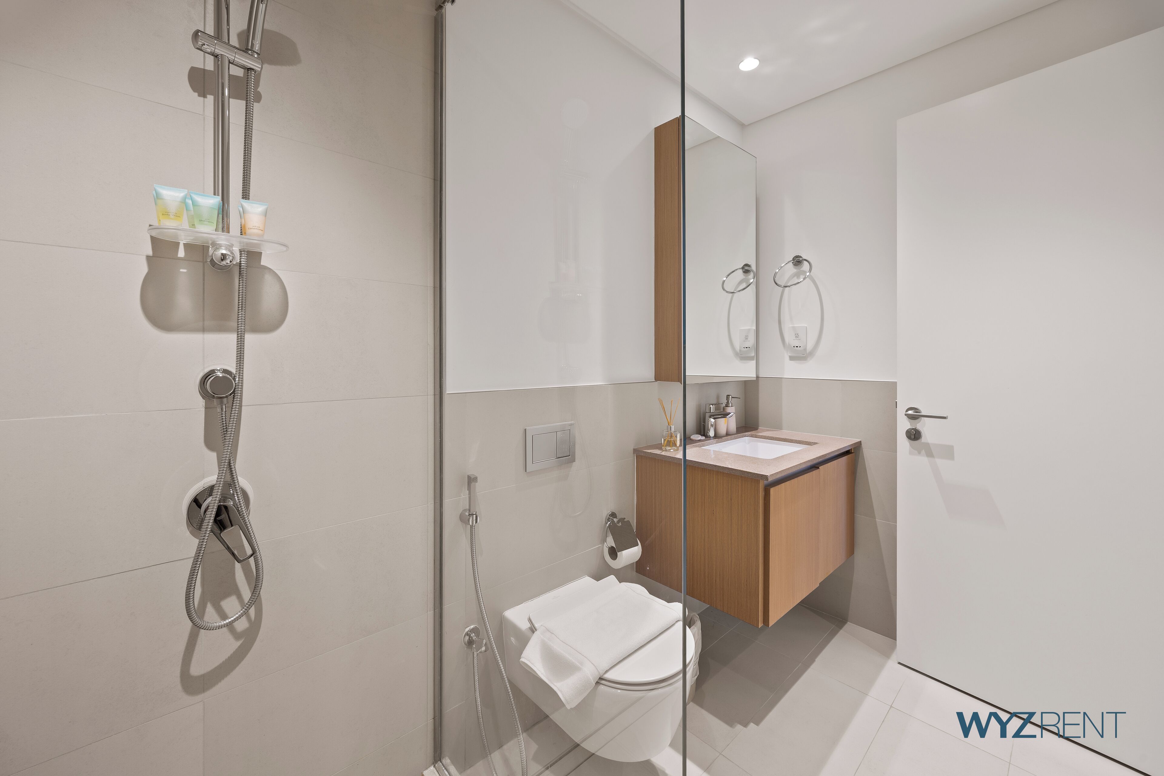 A modern bathroom with a glass-enclosed shower, a wooden vanity, and a mirror.