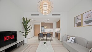 Un salon moderne doté d’un téléviseur à écran plat, d’une table basse, d’un canapé et d’un coin repas avec des chaises.