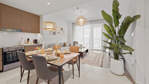 Une cuisine moderne avec un coin repas, comprenant une grande table à manger dressée pour un repas, une grande plante en pot et une vue sur le salon.