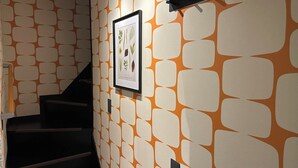 Un escalier avec un mur orné d’un motif et une estampe botanique encadrée.