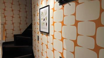 A staircase with a patterned wall and a framed botanical print.