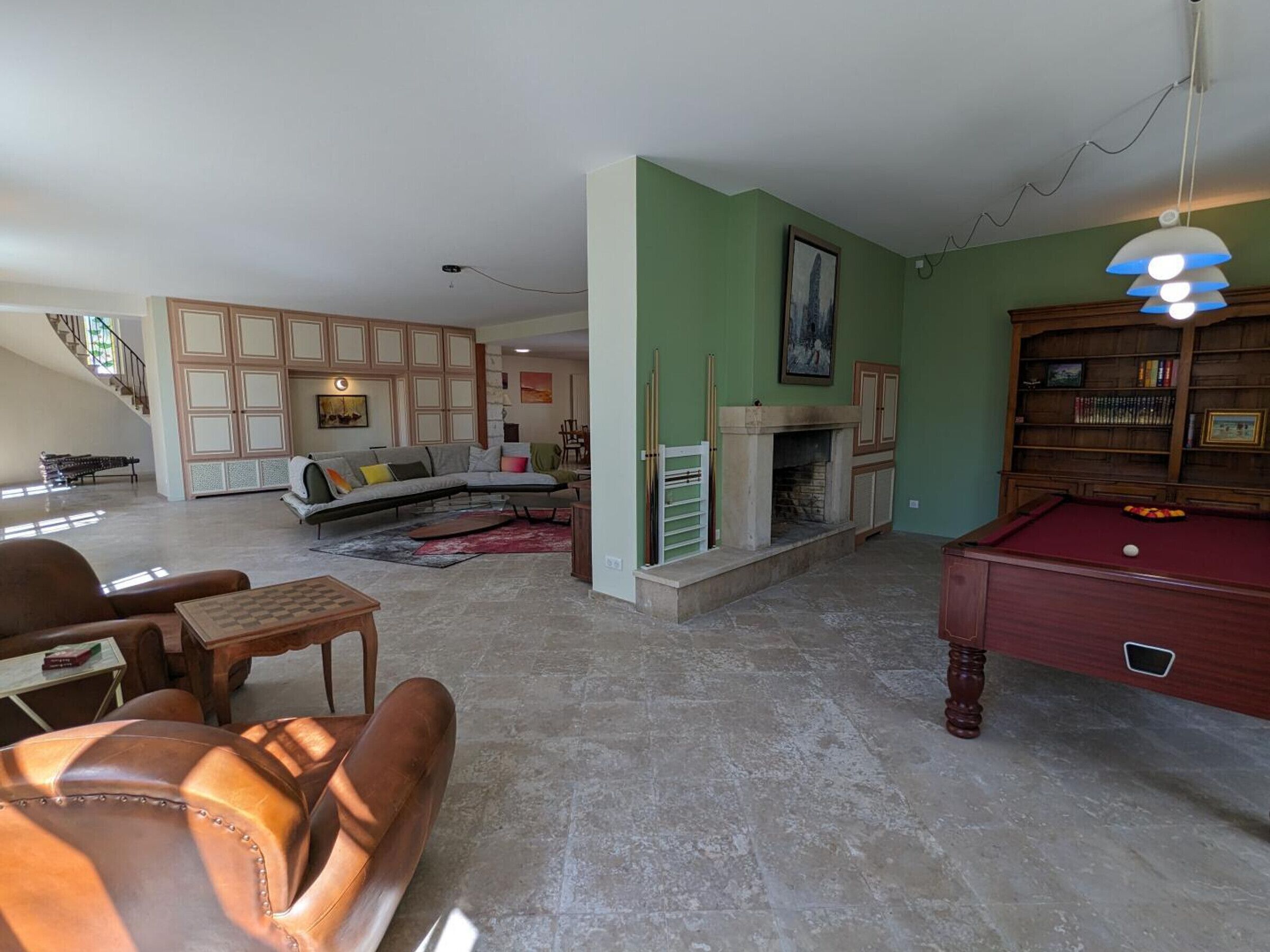 Een ruime woonkamer met een open haard, een pooltafel en een biljartrek.