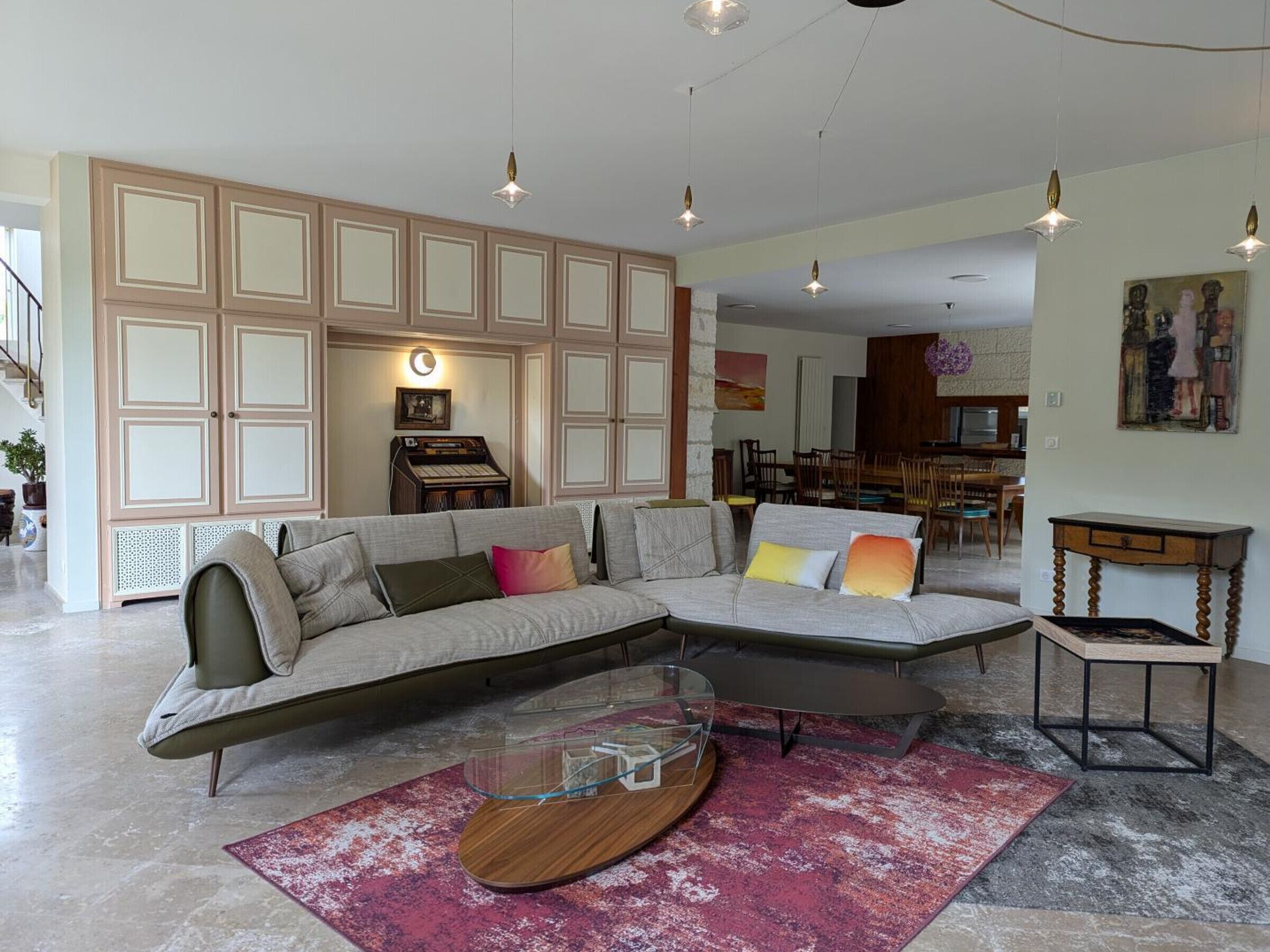 A modern living room with a sectional sofa, a glass coffee table, and a red rug.