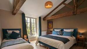 A bedroom with two beds, wooden beams, a window with curtains, and a hanging light fixture. - Large house with private pool, wifi, pets allowed for 15 guests. (Pranzac)