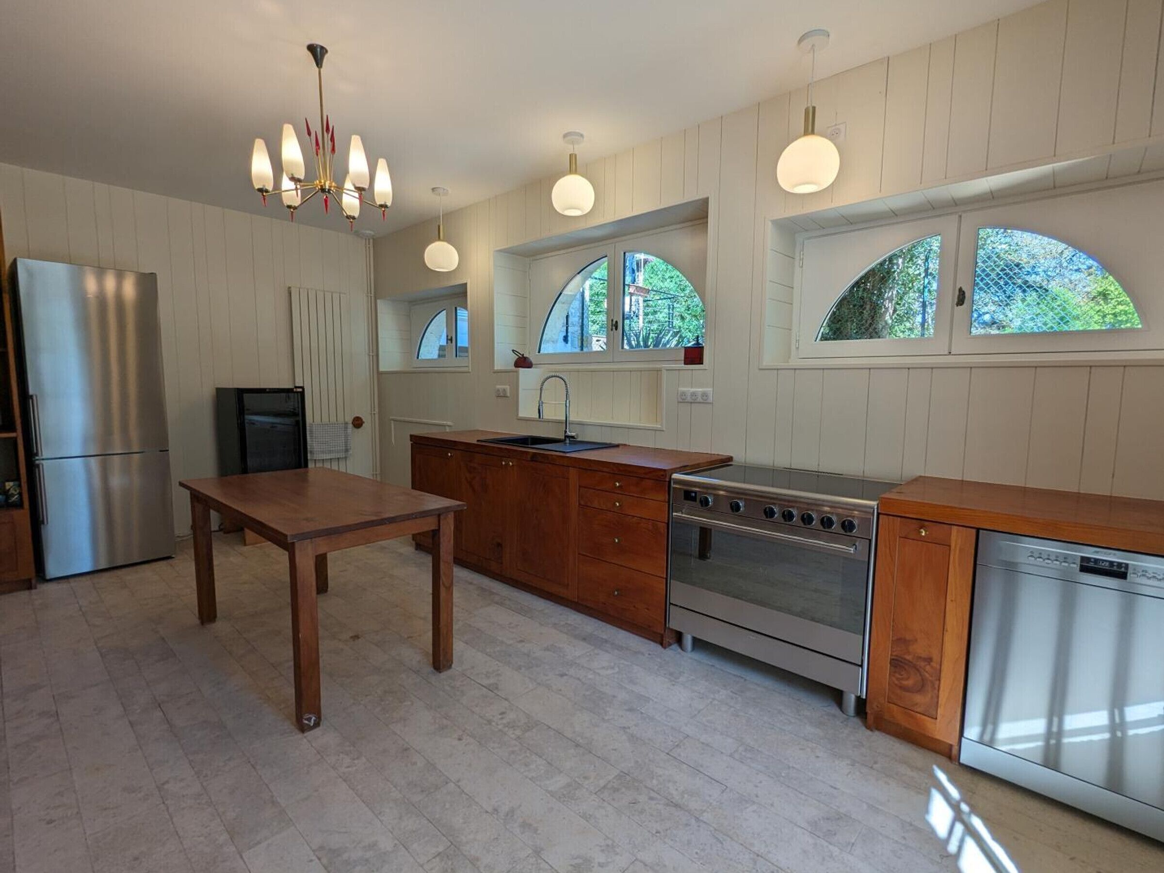 Una cocina moderna con refrigerador de acero inoxidable, mesa de madera y horno empotrado.