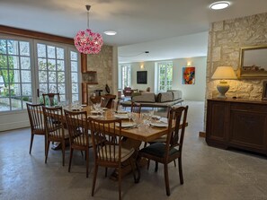 Un vaste espace dédié à la salle à manger, avec une table en bois dressée pour six personnes, entourée de chaises.