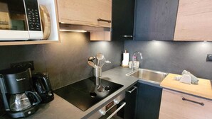 A modern kitchen with a microwave, coffee maker, and a sink. - Charming renovated apartment with Wifi and pets allowed, in the center of Les Gets (Les Gets)