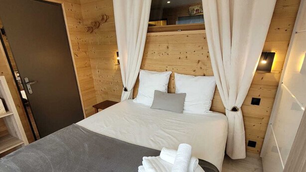 A bedroom with a bed, pillows, a nightstand, and a rolled towel on the floor. - Charming renovated apartment with Wifi and pets allowed, in the center of Les Gets (Les Gets)