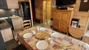 A cozy kitchen with wooden cabinets, a refrigerator, and a television on a wooden stand. - Charming renovated apartment with Wifi and pets allowed, in the center of Les Gets (Les Gets)